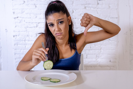 Portrait o f young attractive woman feeling sad and bored with diet not wanting to eat vegetables or healthy food in Dieting Eating Disorders and weight loss concept.の写真素材