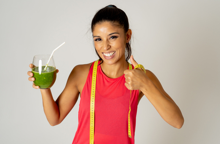 Healthy sport woman drinking fresh green detox cleanse spinach smoothie isolated on grey background in Fitness diet and healthy eating lifestyle concept.の写真素材