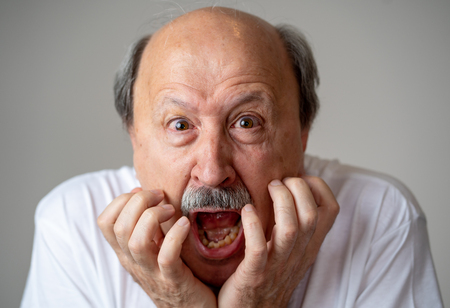 Close up portrait of a scared frightened old man in expression of fear in human emotions and facial expressions isolated in neutral background.の写真素材