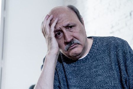 Overwhelmed old senior man suffering alone at home feeling confused sad alone on couch at home in Aging Retirement widower Dementia and Alzheimer concept.の写真素材