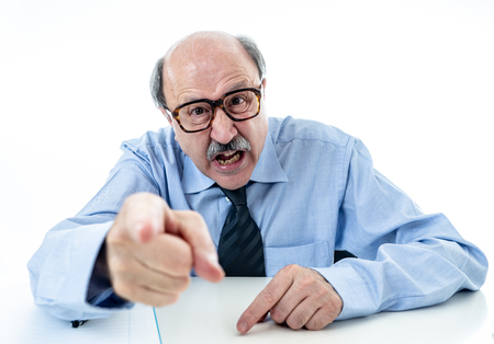 60s senior businessman boss furious shouting and gesturing upset and mad sitting on desk in Managing and Stress Problems at Work isolated on white background.の写真素材