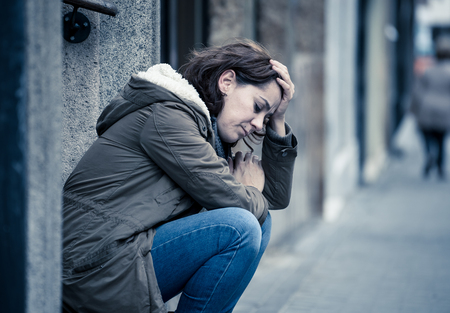 Attractive woman suffering from depression felling sad unhappy heartbroken and lonely sitting in city urban street in Mental health Emotional pain Abusive relationships and loneliness concept.の写真素材