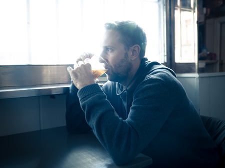 Portrait of a attractive caucasian man drinking beer in a bar pub feeling depressed unhappy and lonely in Alcohol Use Abuse Depression and mental health concept.の写真素材