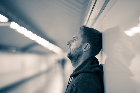 Sad jobless young man crying suffering depression stress sitting on ground street subway tunnel looking desperate leaning on wall alone in Mental disorder Emotional pain Drug abuse and Alcoholism.の写真素材