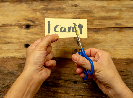 Woman hands holding card with written text i can't do it cutting the letter T with scissors so you read I can in Success and Challenge concept Believe in yourself and Motivation to achieve results.の写真素材