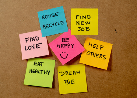 New Year's resolution written on cork board with colorful memo notes of dreams wishes and trendy...