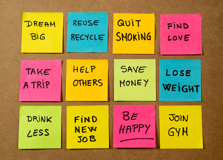 New Year's resolution written on cork board with colorful memo notes of dreams wishes and trendy lettering post its for happy life style Goals and self management motivation concept.の写真素材