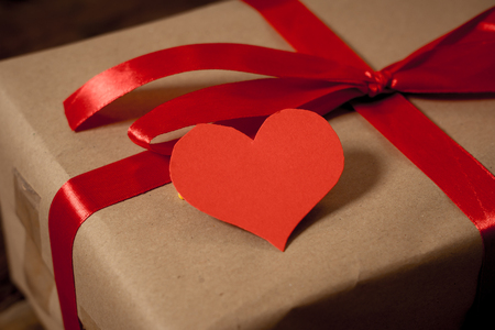 Close up of present gift and heart with copy space for text on wooden background in vintage style in Valentines day decoration, wedding anniversary celebration, greeting card and Love concept.の写真素材