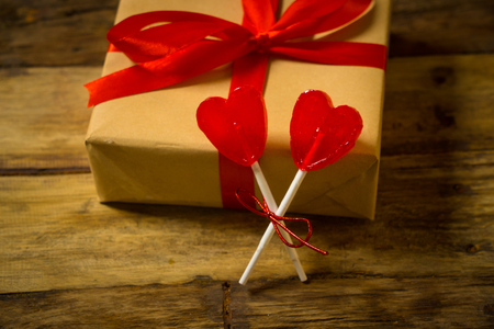Two cute red heart shaped lollipops on rustic wooden table and beautiful romantic mood light and blur background as metaphor of love, togetherness and Valentines day greetings car design concept.の写真素材