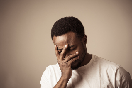 Portrait of african american adult in pain with sad and exhausted face looking concerned, worried and thoughtful in human emotions, facial expression and Depression. Isolated on neutral background.の写真素材