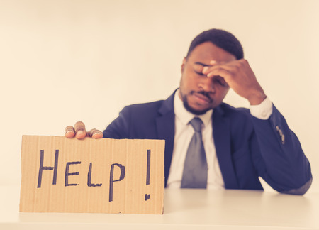 Young attractive and frustrated african american businessman holding message asking for help feeling sad and overworked in corporate job problem, business crisis and unemployment Depression concept.の写真素材