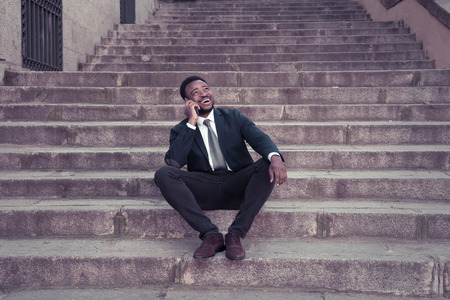 Attractive businessman talking on smart mobile phone on urban stairs street city happy working...