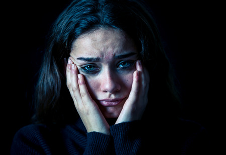 Dramatic closeup portrait of young scared, depressed girl crying alone, feeling hopeless suffering from harassment or domestic violence. Stop child abuse and neglect. Social campaign concept.の写真素材
