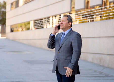 Middle aged businessman talking on smart mobile phone in urban city street in happy people working outside. Social network, freedom, modern technology and Entrepreneur Creative Business concept.の写真素材
