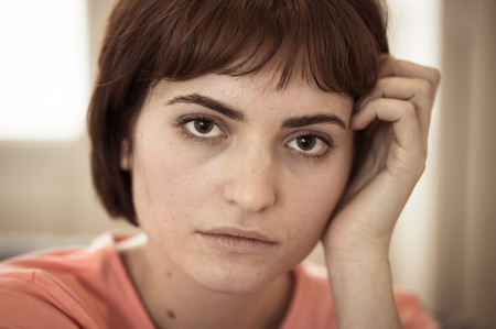 Close up portrait of young attractive woman posing with beautiful smile and bob haircut. Sitting on sofa staring at the camera. In leisure, beauty, modeling and lifestyle concept.の写真素材