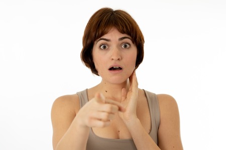 Beautiful young brunette red hired woman with happy face pointing and making surprised gestures and...