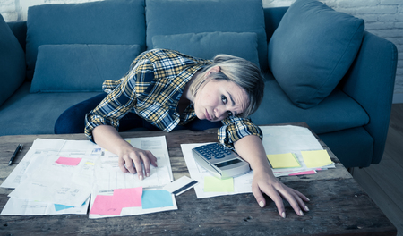 Portrait of worried and desperate young entrepreneur woman accounting home or small business finances feeling stressed not able to pay off debts, bills, rent and expenses. In financial problems.の写真素材