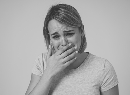 Close up black and white portrait of young sad and anxious woman, crying, looking miserable and hopeless. Feeling sorrow and grief. With white copy space. In facial expressions and emotions concept.の写真素材