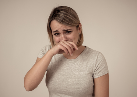 Close up portrait of young sad and anxious woman, crying, looking miserable and hopeless. Feeling sorrow, grief and fear. With white copy space. In facial expressions and emotions concept.の写真素材