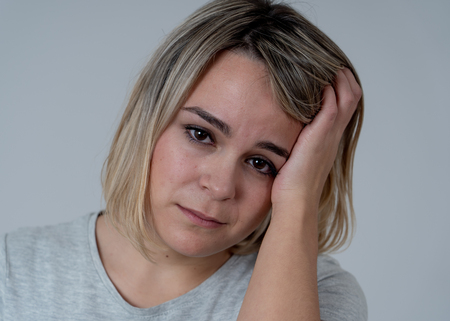 Close up portrait of young sad woman looking worried suffering from headache, Touching her head in pain. In People healthcare, migraines and facial expressions concept.の写真素材