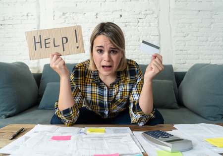 Portrait of worried young woman feeling stressed with too much credit card debts trying to manage business and home finances showing Help sign. In paying off debts, bills and financial problems.の写真素材