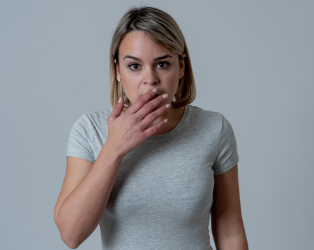 Close up portrait of young woman feeling afraid and shocked hiding her face from something scary. Looking with fear in her eyes. People and Human expressions and emotions concept. Moody light.の写真素材