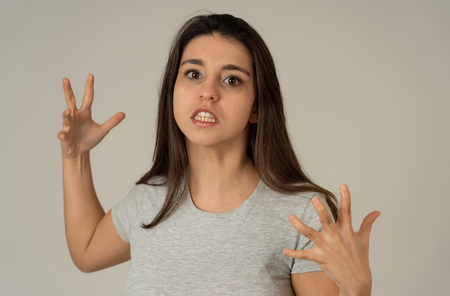 Close up of young attractive frustrated latin woman in stress with furious face. Looking mad and disappointed making angry gestures. In neutral background. In human facial expressions and emotions.の写真素材