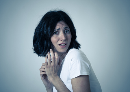 Close up of young woman with frightened eyes, shocked, cowered, cringing. Looking terrified and desperate. People and Human expressions and emotions concept. Isolated on neutral background.の写真素材