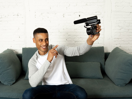 Life style portrait of young happy male blogger on camera screen filming a video tutorial for the...