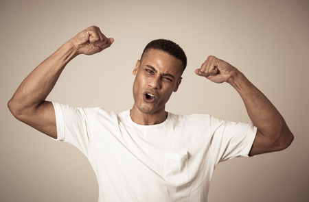 Young strong handsome african american man showing arms muscles smiling proud having fun. In people,...
