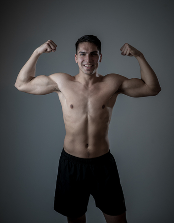 Portrait of strong handsome Athletic man isolated on neutral background. Mixed race latin fitness model posing showing biceps and strong body. In exercise, healthy lifestyle, workout and body care.の写真素材