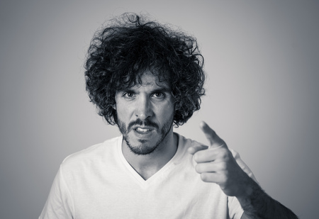 Annoyed young millennial man with an angry face looking mad and furious feeling frustrated. Close up studio shot Isolated on white background. People, Facial expressions and negative emotions.の写真素材
