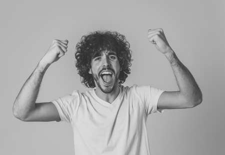Portrait of young happy and shocked man winning the lottery or having great success with surprised face and celebration gestures. In People Facial Expression and positive Human Emotions. Studio shot.の写真素材