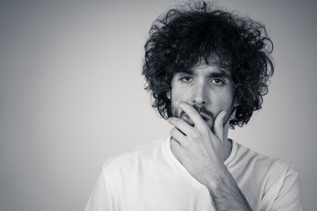 Portrait of young sad man, worried and concerned, looking depressed and desperate. Feeling sorrow and fear. With white copy space. In People, facial expressions and emotions and mental health concept.の写真素材