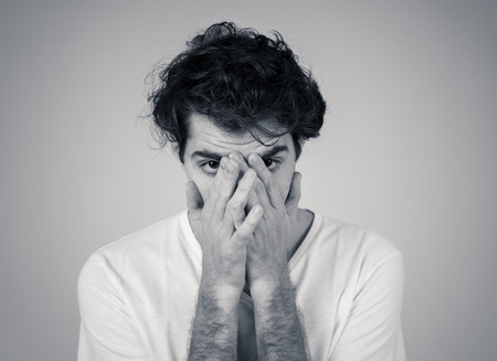 Portrait of young sad man crying in emotional pain looking desperate and distressed. Millennial male suffering from depression. In mental health and sensitive men emotions and feelings reaction.の写真素材