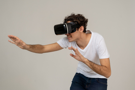 Amazed funny man using VR headset glasses touching and interacting with virtual reality world ,...