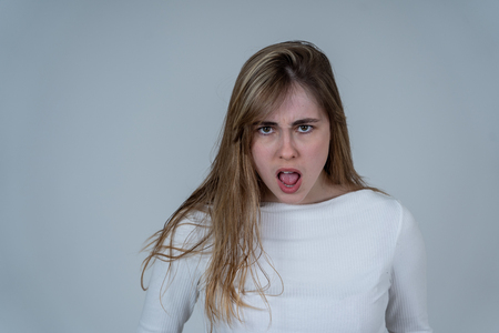 Annoyed irritated young teenager girl looking angry and mad. Feeling frustrated making furious gestures. Close up studio shot Isolated on neutral background. People, Facial expressions and emotions.の写真素材