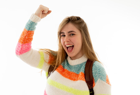 Beautiful millennial teenager girl with backpack and folder smiling and making happy and celebration...