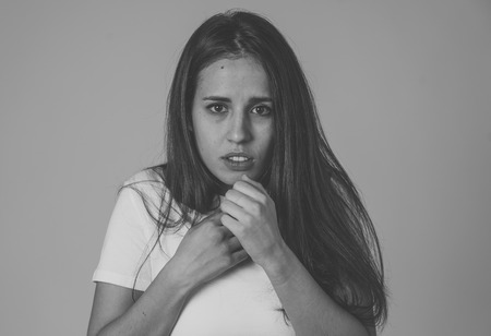 Portrait of young latin woman feeling scared and shocked making fear, anxiety gestures. Looking terrified covering herself. Copy space. In negative human expressions and emotions concept.の写真素材