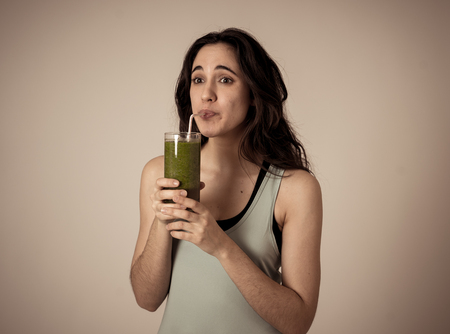 Happy fitness woman drinking green vegetable detox smoothie after running or workout. In Nutrition,...