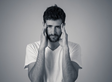 Close up portrait of a young man looking worried and thoughtful suffering from migraines in great pain. Isolated on neutral background. In facial expressions and emotions and heath care concept.の写真素材