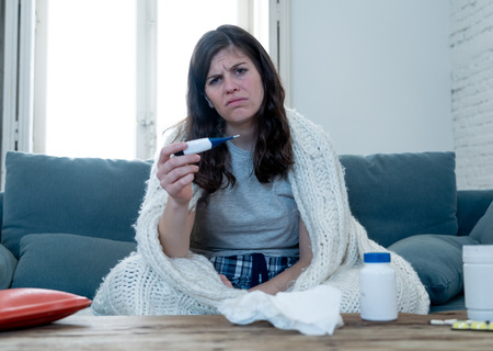 Health care and medicine. Sick woman lying on sofa at home unwell with headache sore nose checking...