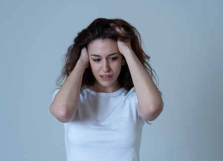 Portrait of young sad woman looking worried in emotional pain. Feeling sorrow and suffering from depression. Isolated in neutral background. In mental health and facial expressions and emotions.の写真素材