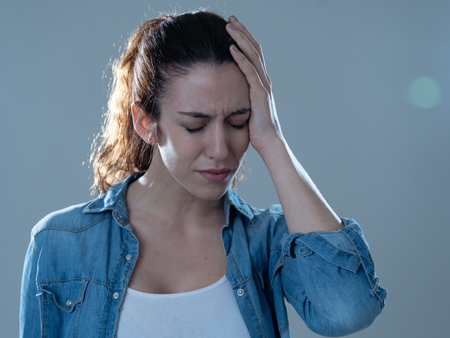 Close up portrait of a young woman looking worried and thoughtful suffering from migraines in great pain. Isolated on neutral background. In facial expressions and emotions and health care concept.の写真素材