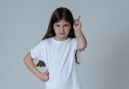 Close up portrait of a cute pretty child looking angry and disappointed pointing with finger against neutral background. In Children feelings and behavior and human emotions and expressions.の写真素材