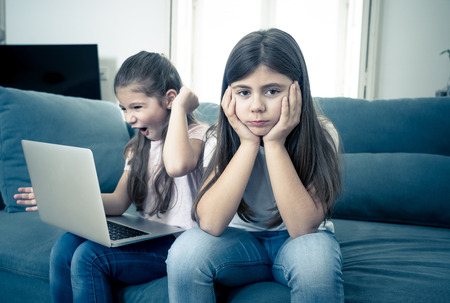 Sibling angry at younger sister spending too much time online using laptop. Digital technology...