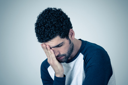 Young sad man, worried and concerned, looking depressed and desperate feeling sorrow. Portrait with...