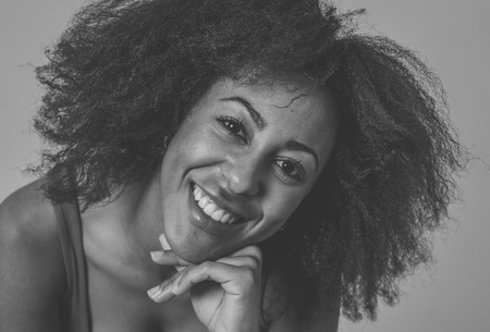 Close up portrait of young african american woman with afro hair style and beautiful smile. Isolated on neutral background. Feeling confident posing and modeling. In lifestyle and beauty concept.の写真素材