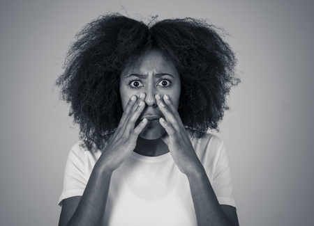 Portrait of young african american woman feeling scared and shocked making fear, anxiety gestures. Looking terrified covering herself. Copy space. In negative human expressions and emotions concept.の写真素材