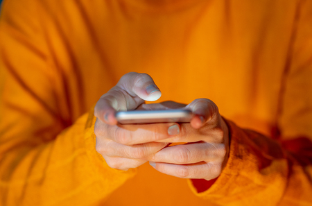 Hands of young woman or teenager sending text on social media app in Internet and Mobile addiction Cyberbullying Communications and Modern technology concept in colorful background and screen light.の写真素材